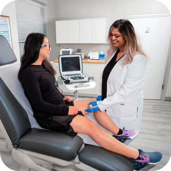 Double certified Dr Kamran Saraf Dr. Shair consults with a patient in a clinical setting, using a tablet to display a diagram of healthy venous anatomy. She explains the details of the anatomy to help the patient understand conditions like chronic venous insufficiency.