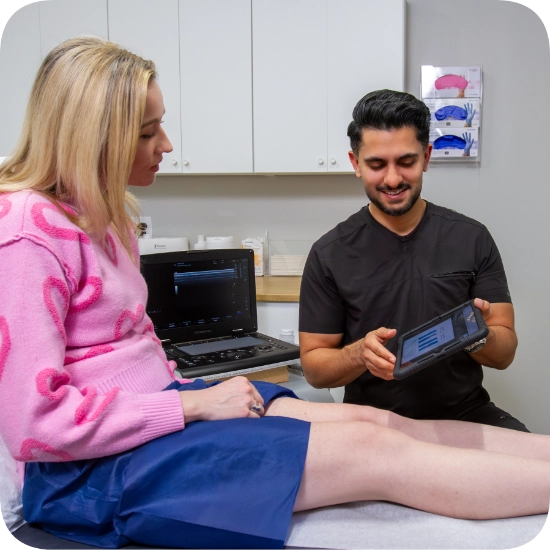 Double certified Dr Kamran Saraf Dr. Akash Mehta performs a Duplex Ultrasound examination on a patient's leg to assess for Varicose Veins and Venous Reflux. The patient is positioned on an examination table in a clinical setting while the provider monitors the real-time ultrasound imagery on the Ultrasound Machine. This vascular assessment procedure is conducted in a professional medical environment equipped with standard diagnostic equipment.